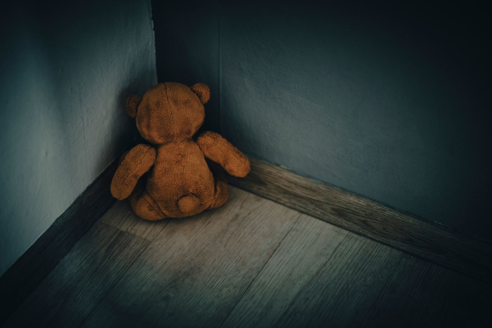 Teddy bear soft toy sitting corner room.Concept of domestic violence against children.